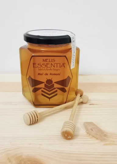 Tarro de miel con cuchara de madera sobre una superficie de madera clara.